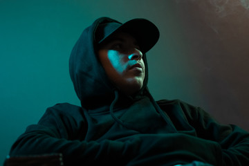 young cool rapper with black hoodie and cap looking sideways