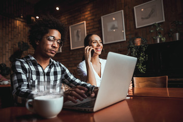 Multiethnic business team meeting at cafe, working using laptop and smartphone