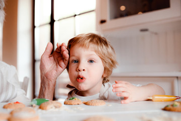 A midsection of senior grandmother with small toddler boy making cakes at home.