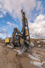 Drilling machine in a construction site surrounded by rock and mud