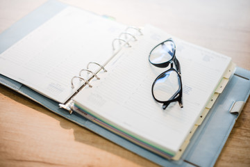 open notebook and black glasses laying on the table