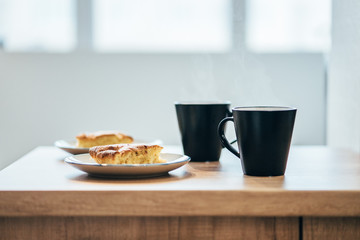 black cup of coffee and apple cake on wooden table 