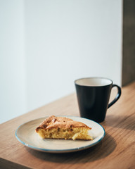 black cup of coffee and apple cake on wooden table 