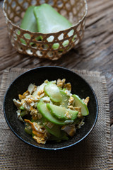 Fresh chayote fruits (Sechium edulis) stir fried with egg and garlic in bowl on wood background