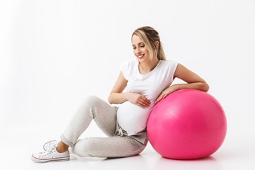 Fototapeta na wymiar Beautiful young pregnant yoga fitness woman posing isolated over white wall background make exercises with ball.