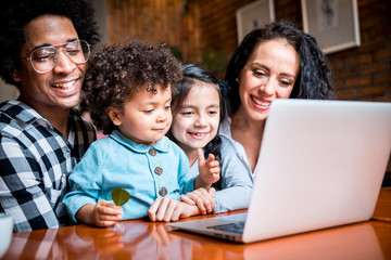 Happy multiethnic family having fun while using laptop together
