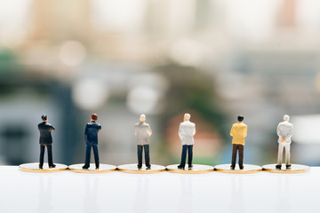 Miniature people: Group of small businessmen standing on coin with city backgrounds. Money, Financial, Business Growth concept.