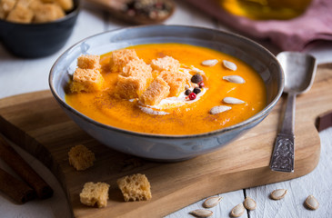 Delicious pumpkin soup in a bowl with croutons on white wood