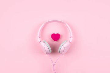Pink headphones and heart on pink background. Minimal Music concept. Top view. Flat lay