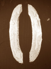 Number 0 in stencil on metal wall in brown tone.