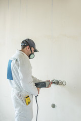 A man drills a wall with a perforator. A man works with construction tools.