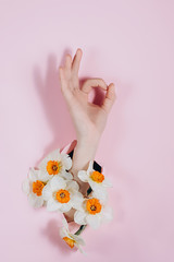 Hand show is showing a gesture Okay, ok, can be seen through a hole in pink paper with flowers....