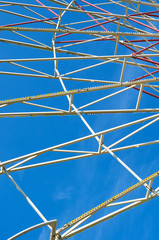 The metal construction of the carousel Ferris wheel against the blue sky.