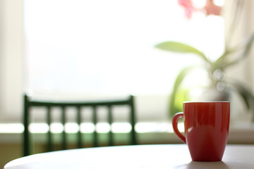 Red Cup on the table against the background of the window. sunny warming morning