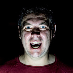 Stylish portrait of adult caucasian man. He smiles like maniac and seems like maniac or crazy. Low-key lighting. Angry man, fear concept. Isolated on black.