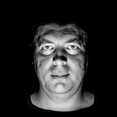 Stylish portrait of adult caucasian man. He smiles like maniac and seems like maniac or crazy. Black and white shot, low-key lighting. Angry man, fear concept. Isolated on black.