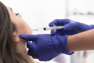 Doctor injecting substance in patient jawline