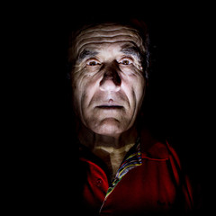 Portrait of old caucasian man. Low-key lighting. Isolated on black.