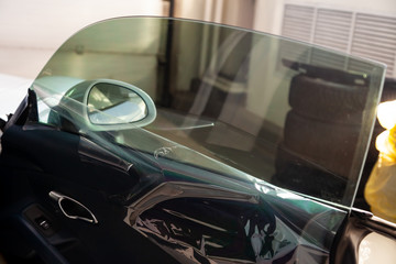 The process of tinting the glass of the car in the workshop for the installation of additional...