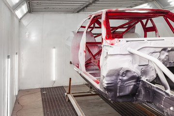 Painting in red and black color of the inside of the frame of the car disassembled after the accident in the workshop for body repair and tuning of vehicles