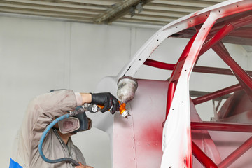 A man master in protective overalls and a mask holds a spray bottle in his hand and sprays red...