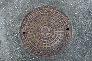 cast iron manhole on asphalt background