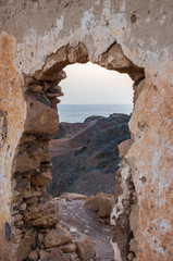 Wall with gate of a building demolished on a cliff facing the sea