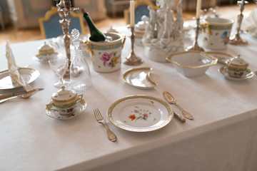 Wedding table decoration with expensive retro royal majesty porcelain service plates and cutlery in a palace