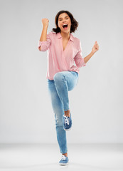 fashion, success and people concept - happy smiling young woman in striped shirt, jeans and...