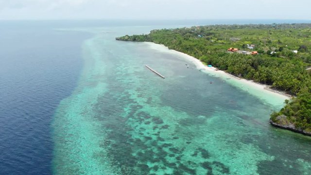 Aerial: Flying over tropical beach turquoise water coral reef , Tomia island Wakatobi National Park Indonesia Maldives Polynesia white sand beach
