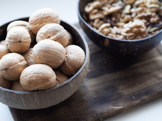 Walnuts in the cap on wooden background with copy space; coconut bowls with nuts; a healthy diet in eco-friendly dishes; nutrition and snack for busy people; concept of healthy lifestyle