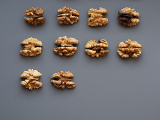 Obraz na płótnie Canvas Row of walnuts on gray and blue textured background with a copyspace; Top view of kernel halves; close up food photo from above; snack and nutrition, vitamins and minerals;