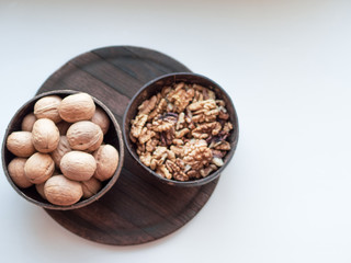 Walnuts in the cap on wooden background with copy space; coconut bowls with nuts; a healthy diet in eco-friendly dishes; nutrition and snack for busy people; concept of healthy lifestyle