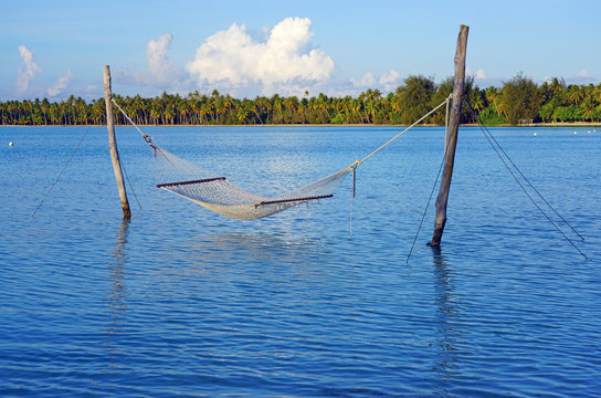 Hammock with a view, planted in the azure waters of the Bora Bora lagoon, French Polynesia