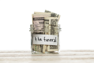 Saving jar with money for the funeral on white wooden table isolated
