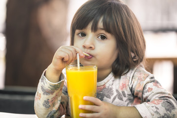Little girl in a cafe drinking juice