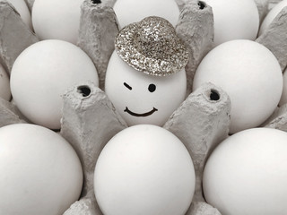 A box of eggs. Smiling egg in the hat.