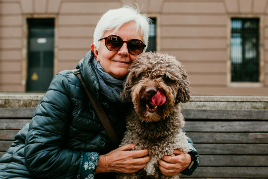 .Middle-aged Woman With White Hair Enjoying Her Spanish Spaniel By The City Of Gijón, In Northern Spain. Close Relationship Between The Dog And Its Owner. Lifestyle