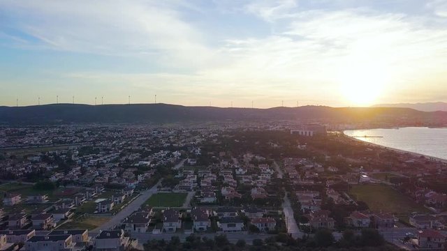 4K hd aerial dolly sideways drone shot, during golden hour, mountains in the background, evening time, silence in city, in ilica beach, cesme, izmir province, turkey