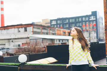 beautiful teen girl long-haired teenager in yellow clothes on the background of the cityscape on...