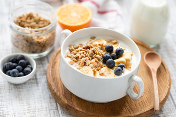 Healthy breakfast cereals granola with milk and fruits in a bowl on wooden table background....