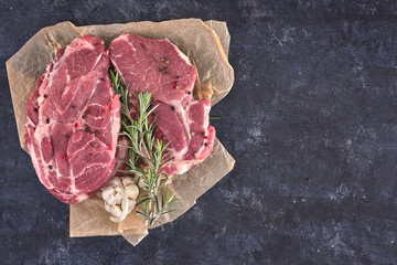 Raw meat steak on dark background. Copy space text concept. Fresh rosemary.