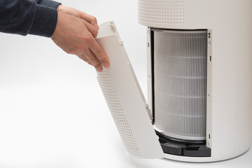 A man's hand turning an air purifier's filter into a new one.