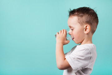child drinks water on a turquoise background