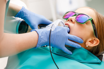 Elementary age girl receiving dental radiography or X-Ray in pediatric dental clinic