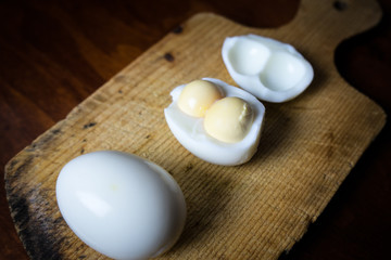 two eggs with double yolks on a cutting board.