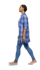 Side view of a young black girl walking in jeans and a checkered
