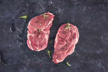 Raw meat steak on dark background. Copy space text concept. Fresh rosemary.