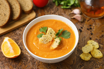 Rich in vegetable protein lentil soup puree .  toast and lemon . tomatoes and greens . brown textured background.