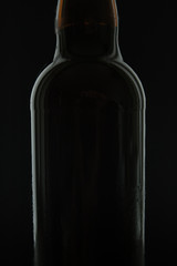 Black beer bottle with water drops isolated on black background with space